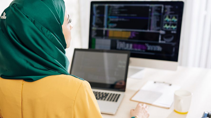 Woman in an emerald hijab programming on her computer