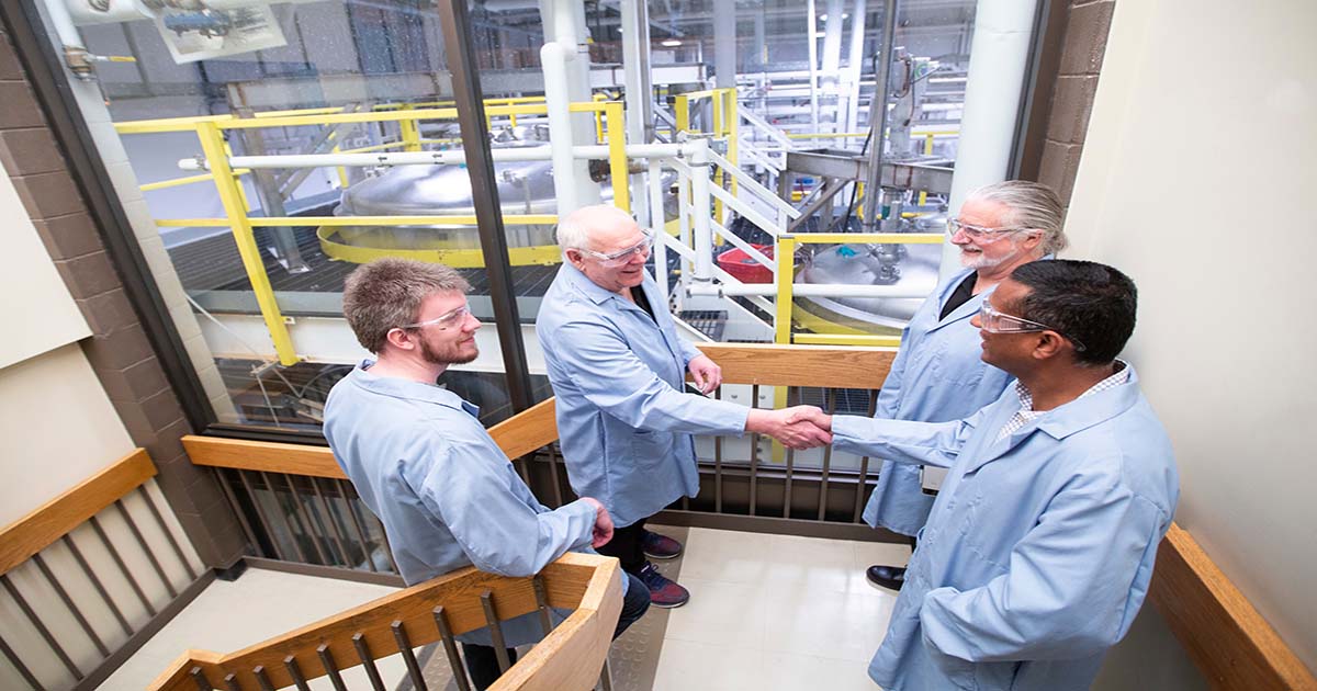 Four Scientists Conversing in a Stairwell Overlooking their Lab