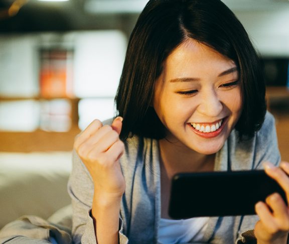 excited asain woman watching something on phone