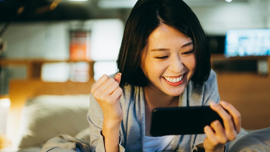 excited asain woman watching something on phone