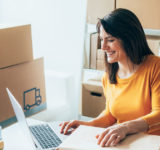 woman in orange top smiling at computer
