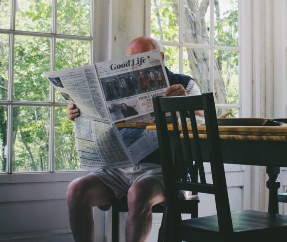 Äldre man läser tidningen.