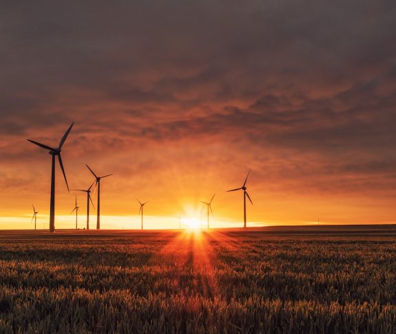 Vindkraftverk i röd solnedgång för att relatera till grön innovation
