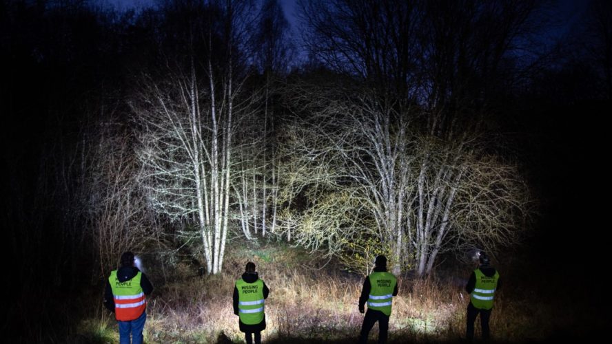 Missing People volontärer som lyser med ficklampor i mörkret