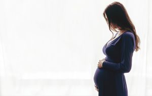 Pregnant woman standing against the window