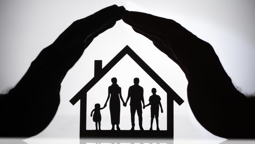 Silhouette Of A Person's Hand Protecting House With Family Figures
