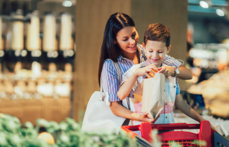 Mother and son buying fruit at grocery store or supermarket - shopping, food, sale, consumerism