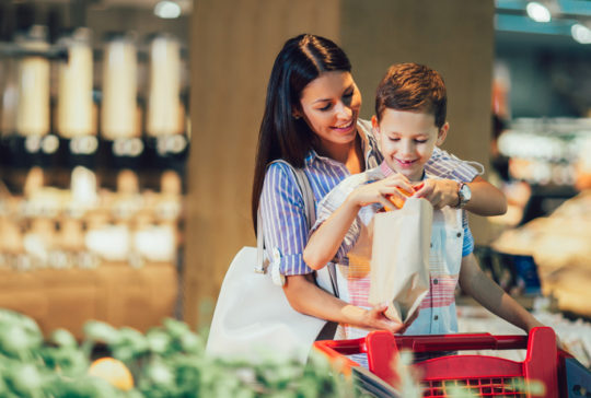 Mother and son buying fruit at grocery store or supermarket - shopping, food, sale, consumerism