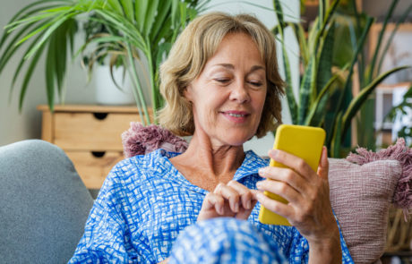 50-60 years old pretty female adult relaxing on the sofa and using smartphone
