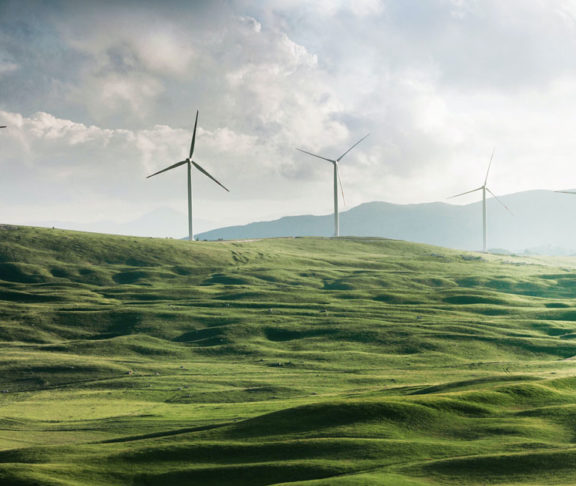 Wind turbines set amongst a green landscape of fields and hills