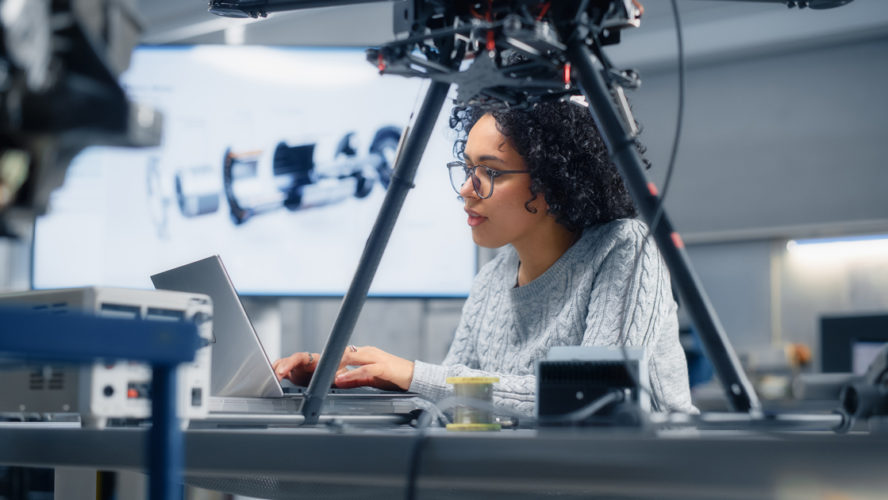 Concentrated Black Female Engineer Writing Code. Developing Software for Drone Control in the Research Center Laboratory. Technological Breakthrough in Flight Industries Concept.