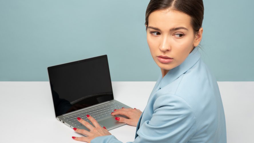 Kvinna vid dator som kollar över axeln.