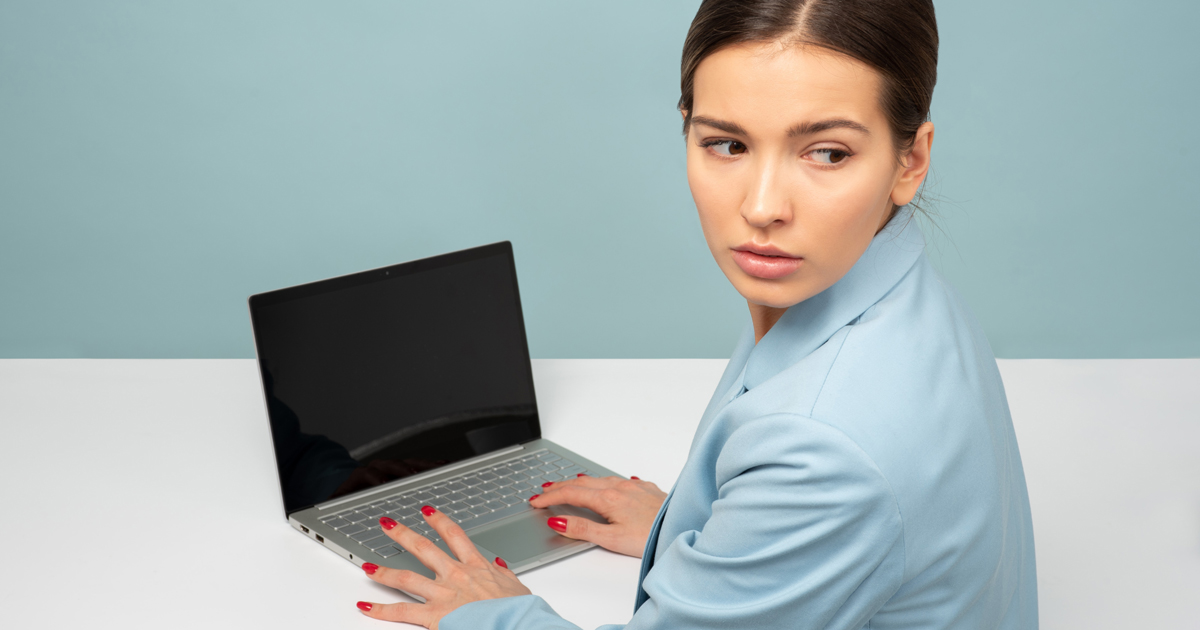 Kvinna vid dator som kollar över axeln.