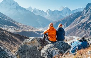 Couple resting on the Everest Base Camp trekking route near Dughla 4620m. Backpackers left Backpacks and trekking poles and enjoying valley view with Ama Dablam 6812m peak and Tobuche 6495m
