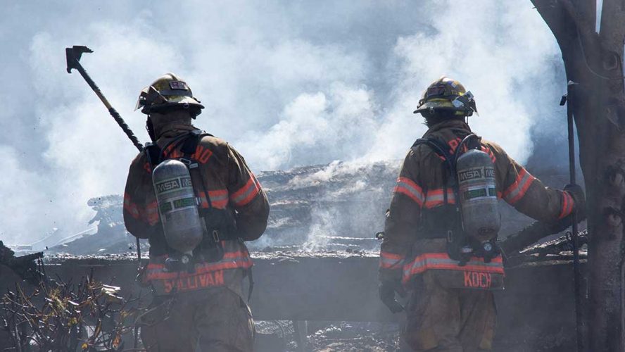 To brandmænd kigger på rygende brandtomt