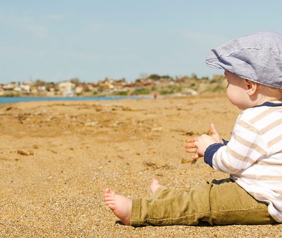 Lille dreng sidder ved stranden