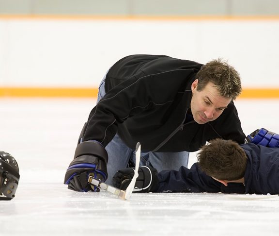 Peewee hockey player receiving help after an injury