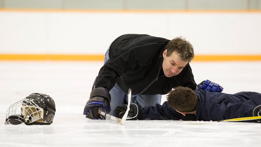 Peewee hockey player receiving help after an injury