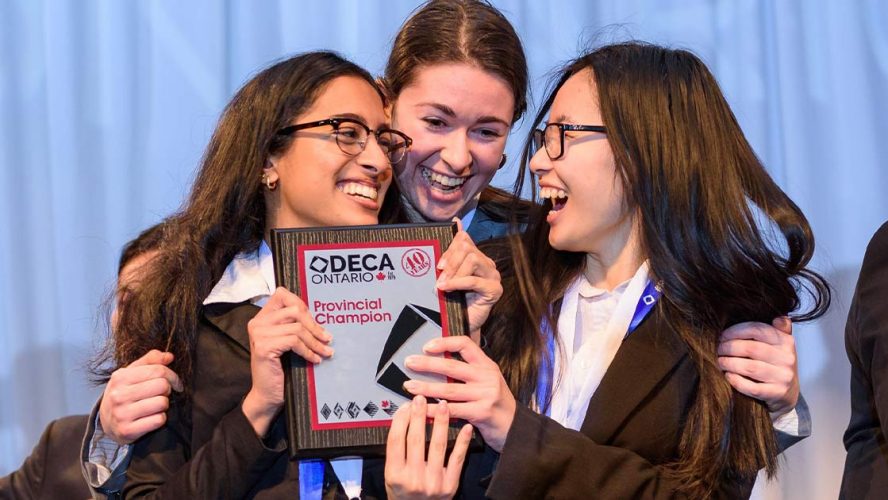 Three girls clutching the DECA Provincial Champion award