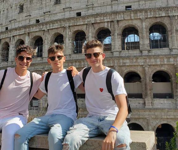 Three high school students in front of the Roman Colosseum