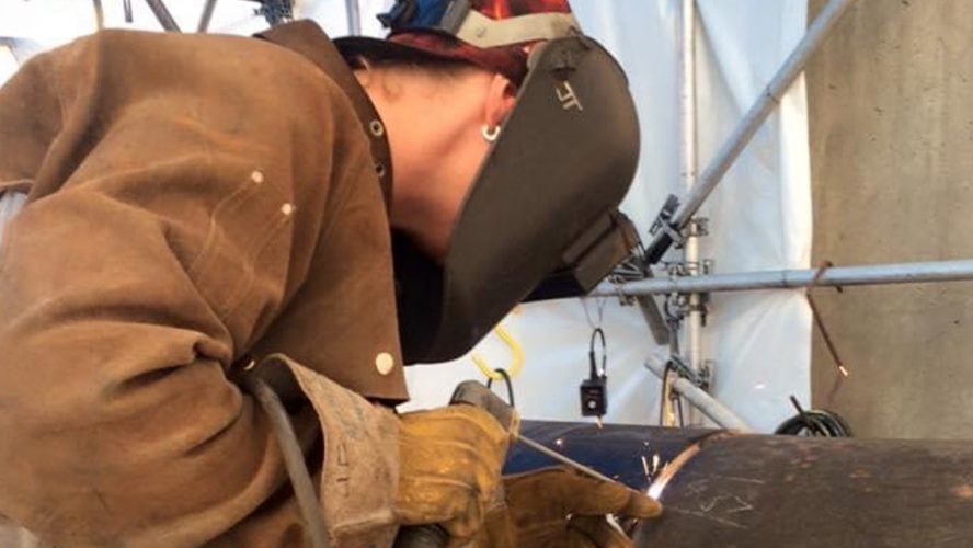 Jill Timushka welds the open root on a pipe in the 5g position