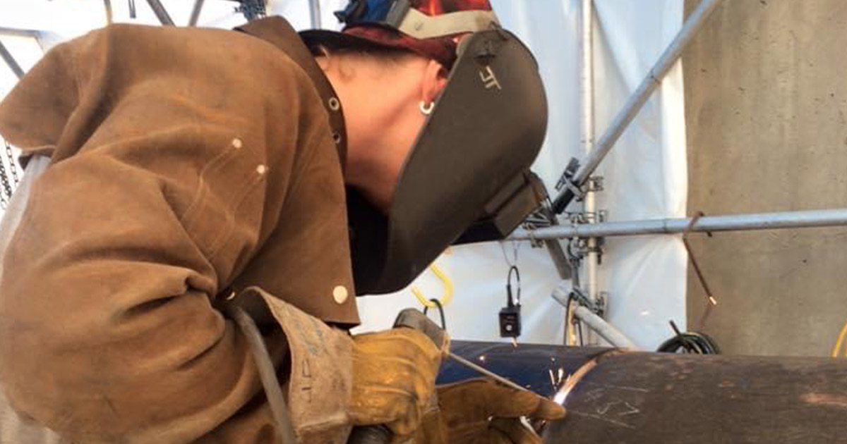 Jill Timushka welds the open root on a pipe in the 5g position