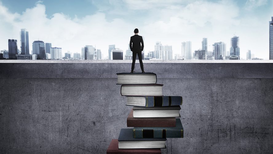A man standing on a foundation of books while facing the world