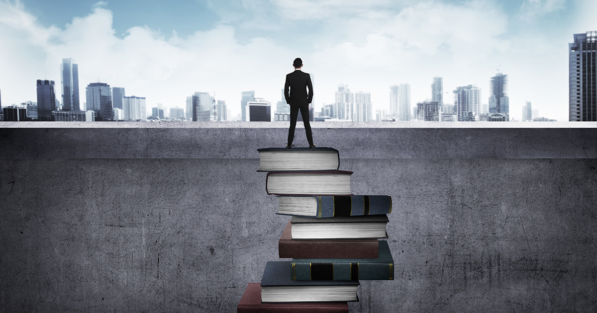 A man standing on a foundation of books while facing the world