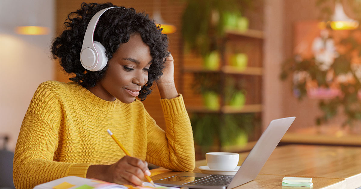 Woman wearing headphones and working on laptop