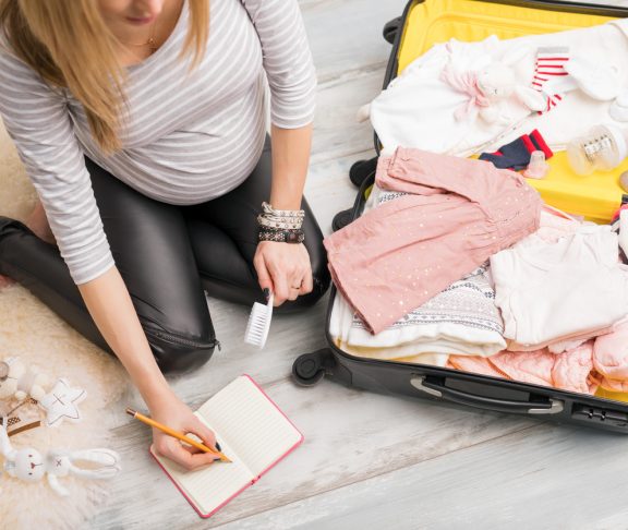Pregnant woman packing for hospital and taking notes