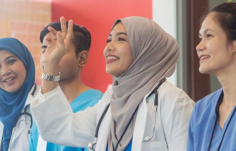 Hijabi doctor smiling and raising her hand