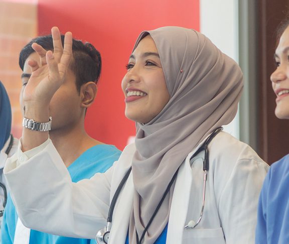 Hijabi doctor smiling and raising her hand