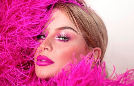 Close-up of Gigi Gorgeous in a hot pink feather boa outfit