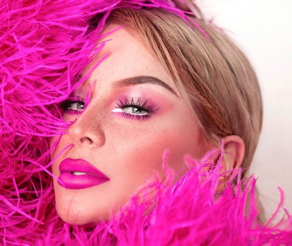 Close-up of Gigi Gorgeous in a hot pink feather boa outfit