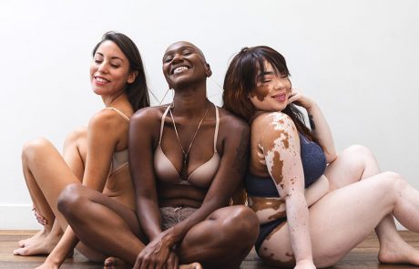 Three models smiling and sitting on the floor together