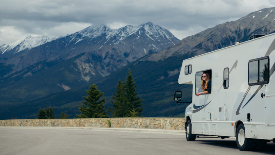 Woman leaning out of RV with mountains in the background