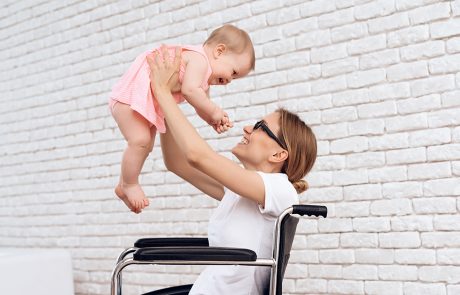 kobieta na wózku inwalidzkim trzymająca niemowlę w ramionach