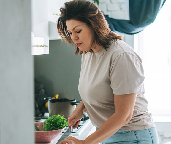En kvinne som skjærer paprika på kjøkkenet