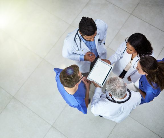 High angle shot of a diverse team of doctors using a digital tablet together