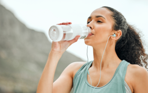young woman taking a break from working out to drink water
