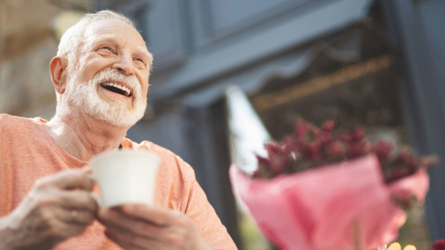 Laughing elderly man drinking tea outdoors