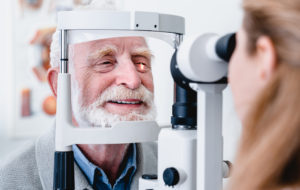 Smiling cheerful elderly patient being checked on eye by female ophthalmic doctor
