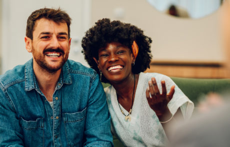 Young multiracial couple smiling because solved conflict at couple therapy session with a counseling adviser and. Diverse spouses being happy with a psychologist advises. Copy space.