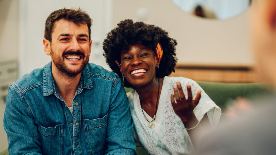 Young multiracial couple smiling because solved conflict at couple therapy session with a counseling adviser and. Diverse spouses being happy with a psychologist advises. Copy space.