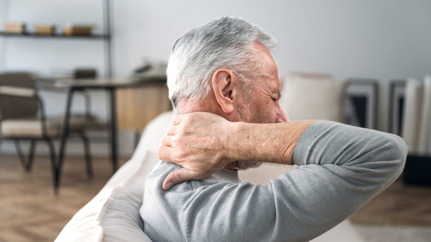Elderly man rubbing hard pain in neck and massaging tense muscles