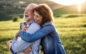 Side view of senior couple hugging outside in spring nature at sunset