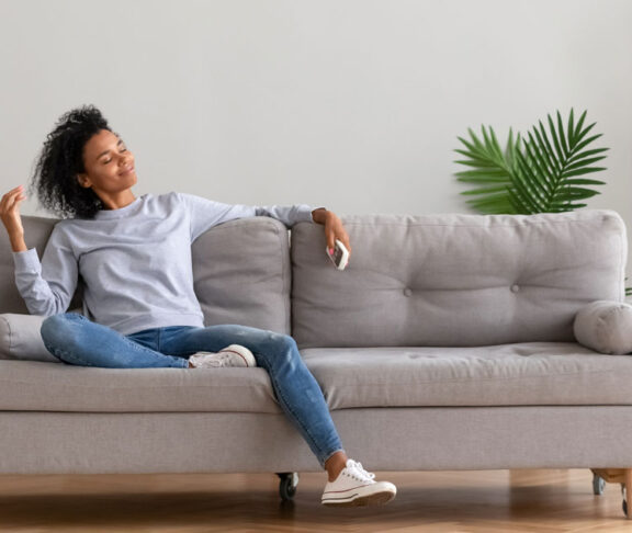 African young relaxed woman sitting on couch breathing fresh air