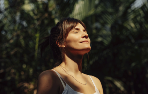 Beautiful Happy Woman Enjoying the Warm Sunlight in a Tropical Public Park
