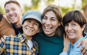 Happy multiracial senior women hugging each other outdoor - Group of multigenerational people having fun at city park - stock photo