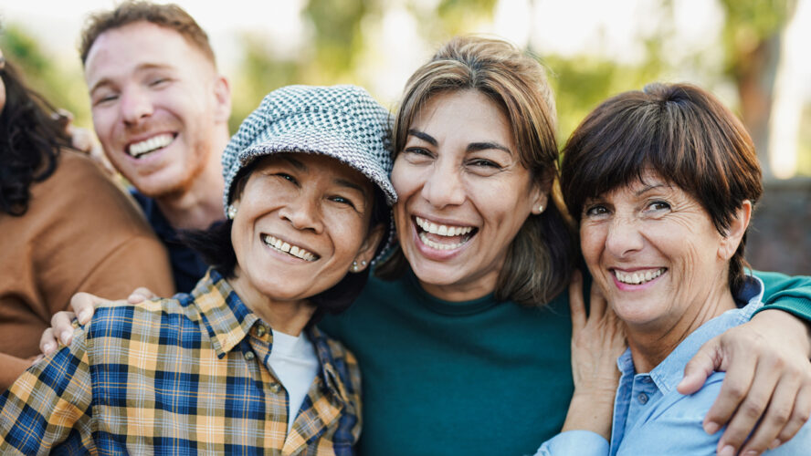 Happy multiracial senior women hugging each other outdoor - Group of multigenerational people having fun at city park - stock photo